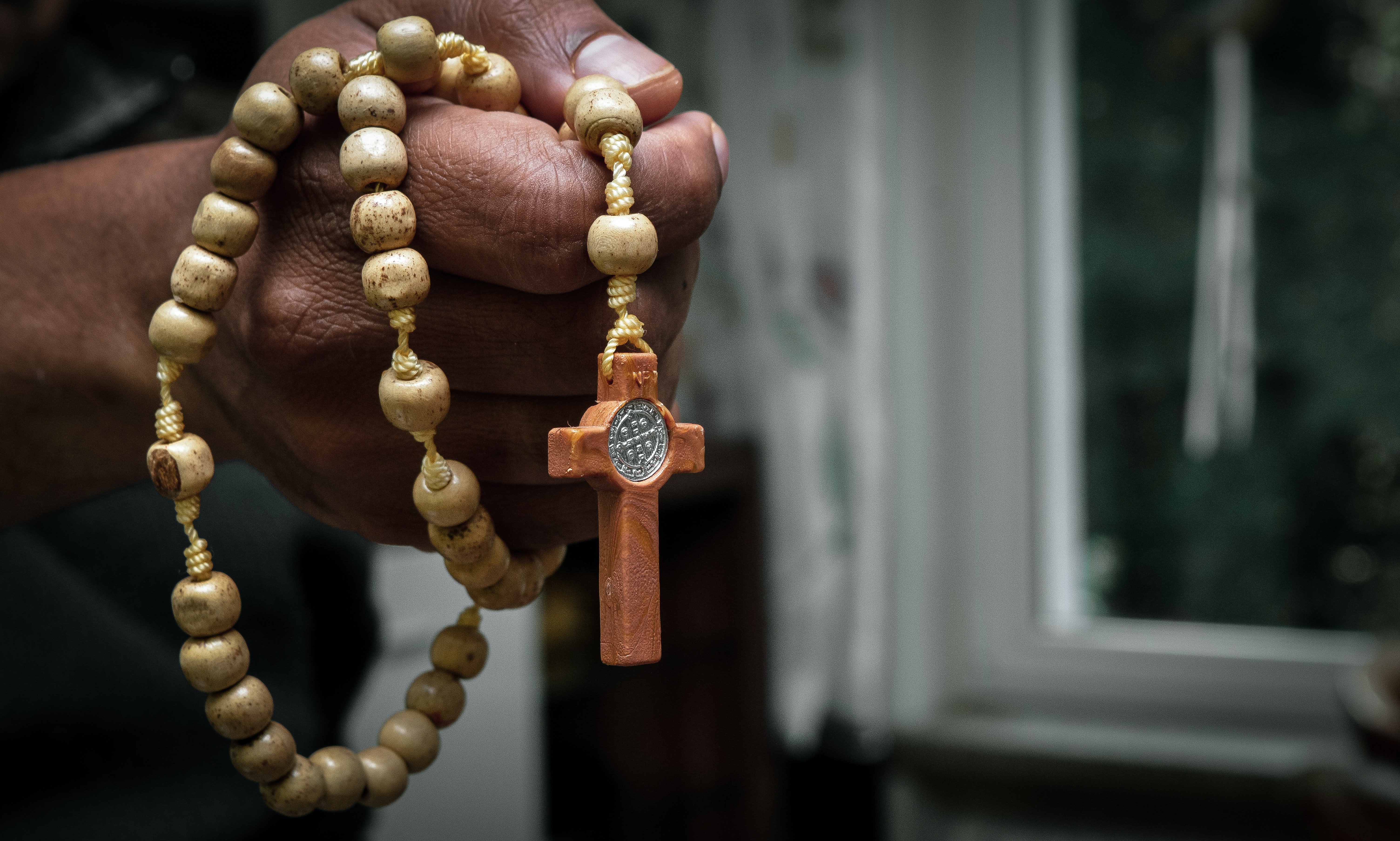 brown rosary cross held on hand