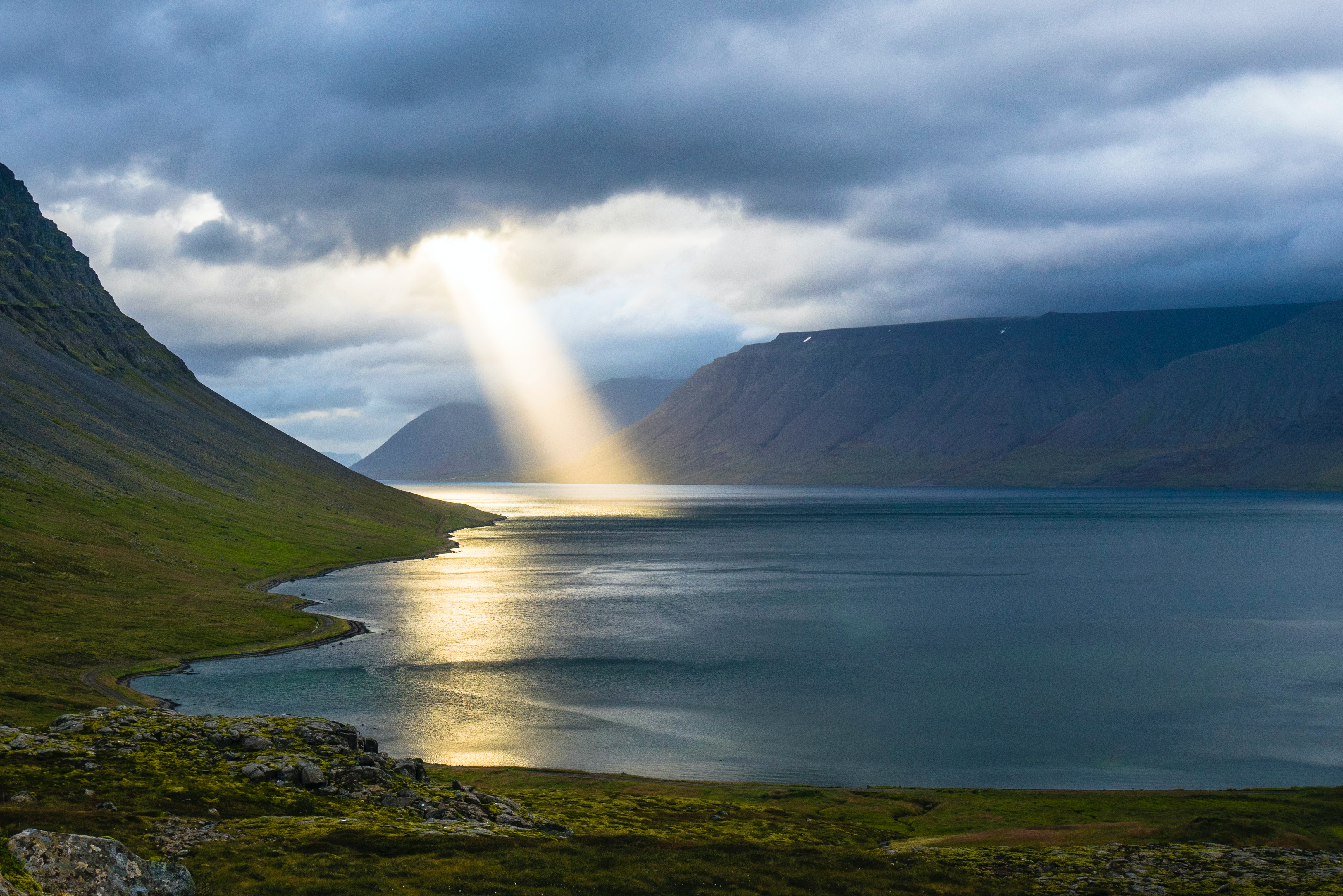 sunlight through clouds onto water and mountain